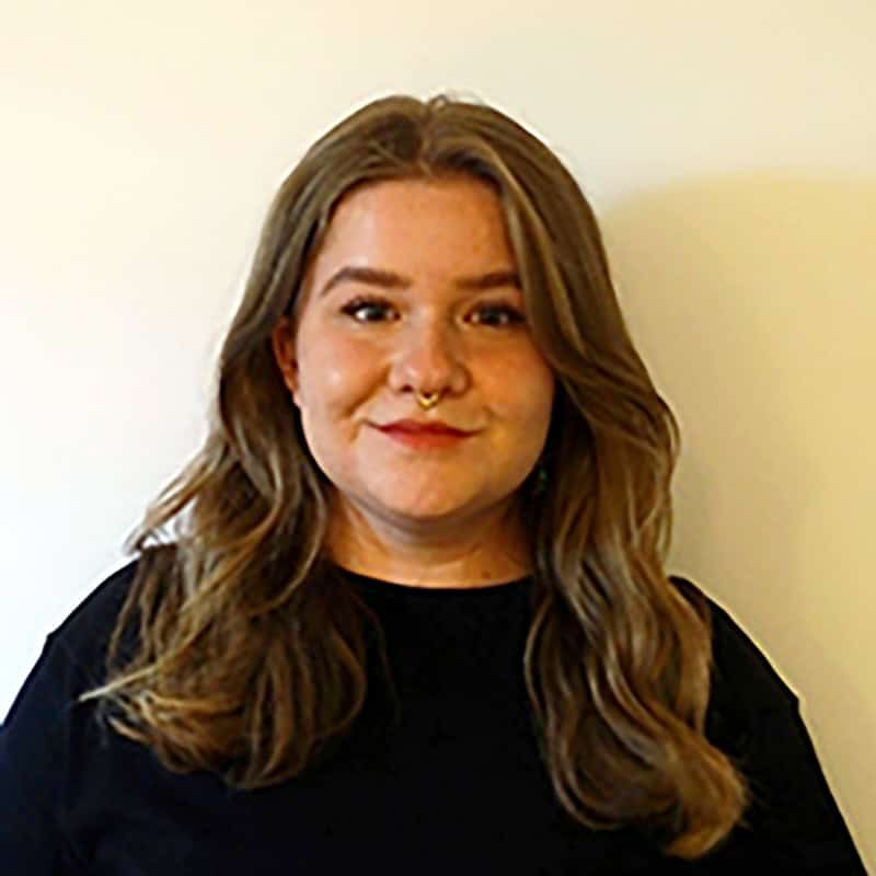 Schwuler, bisexueller, queerer und trans* Person in München, lächelnd, vor weißem Hintergrund.