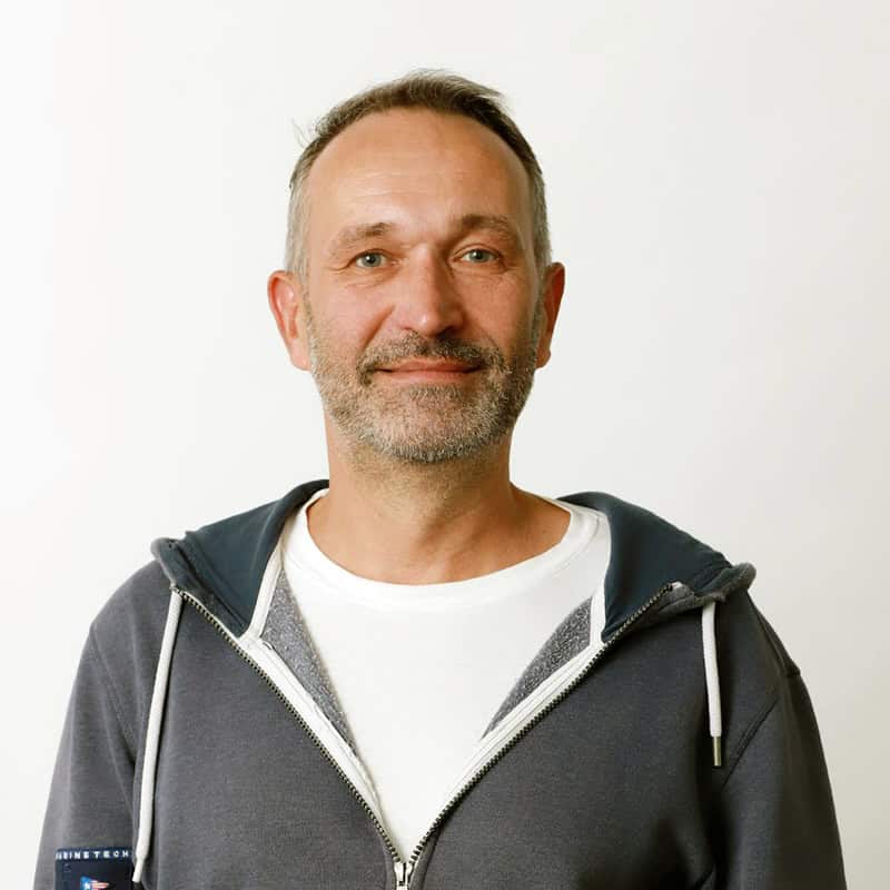 Mann in grauer hoodie und weißen t-shirt vor weißem Hintergrund.